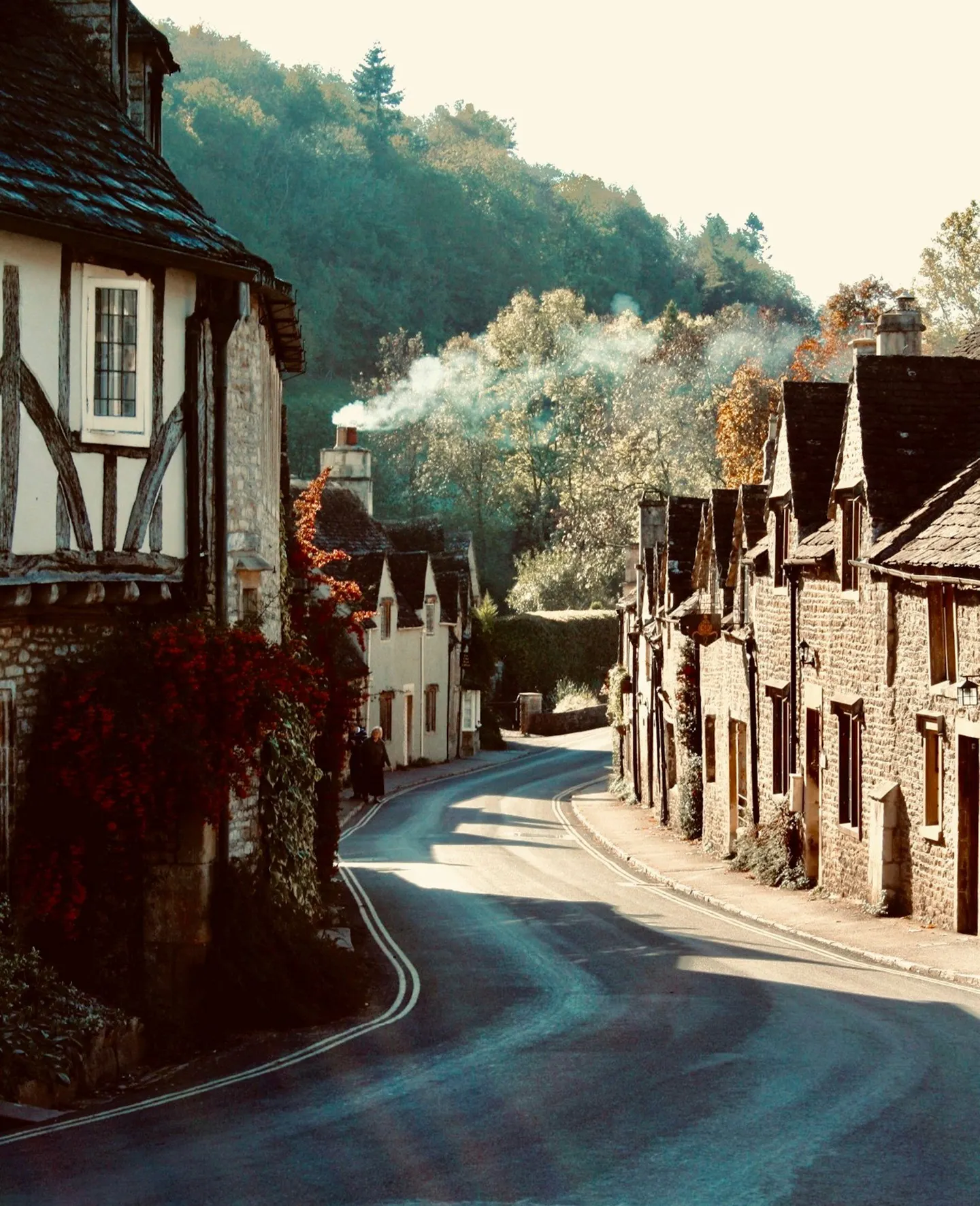 Photo of Castle Combe, Wiltshire — the Street in autumn, curving down through the village between stone cottages.