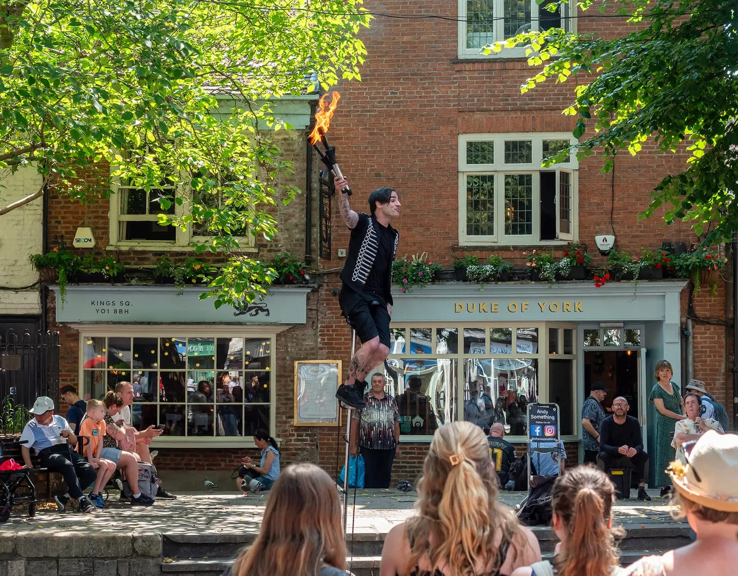 Photo of York, North Yorkshire — a unicycling fire juggler entertaining the crowd in King's Square.
