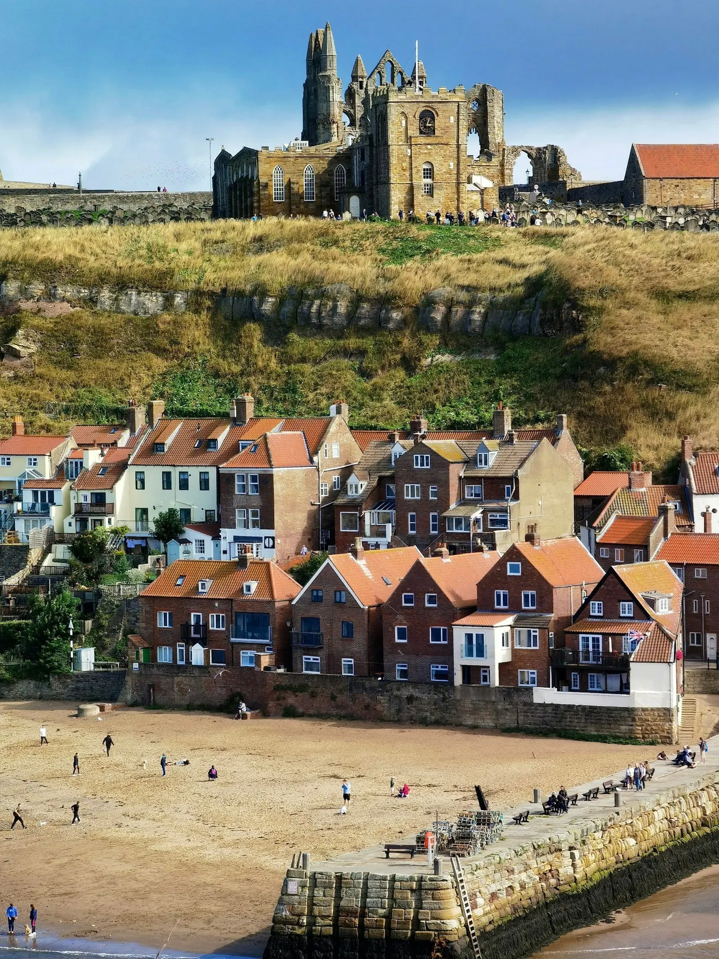 Photo of Whitby, North Yorkshire — the abbey ruins above the red roofs of the East Side and Tate Hill Sands.